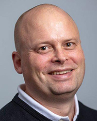 Porträttbild på man som ler in i kameran