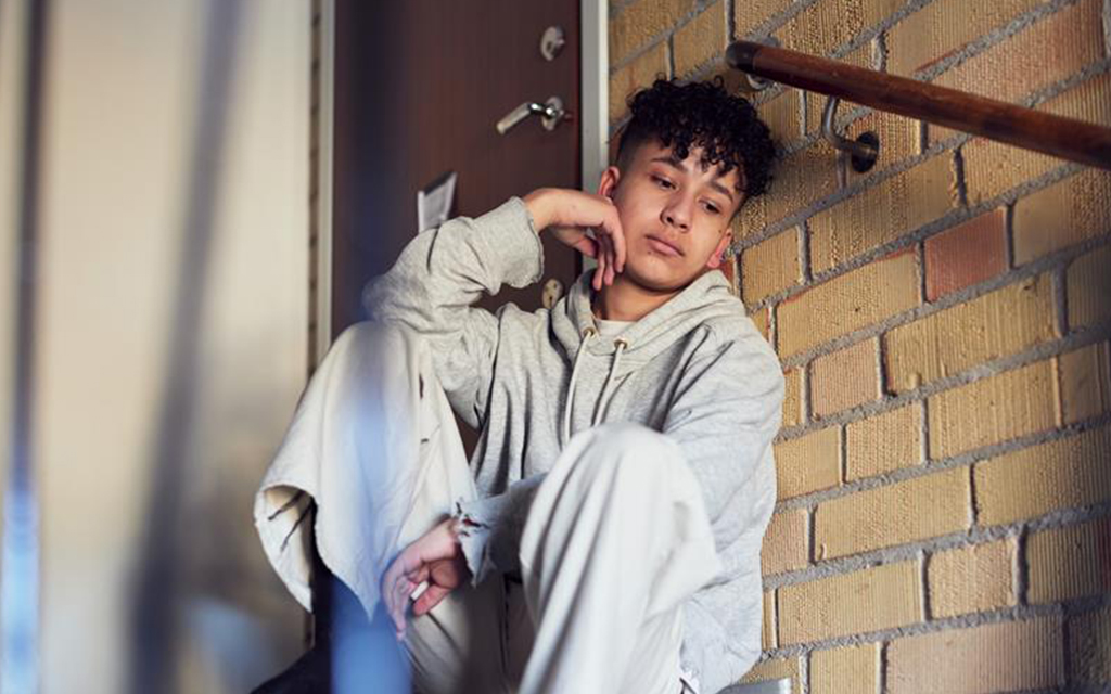 En ung person sitter i ett trapphus.